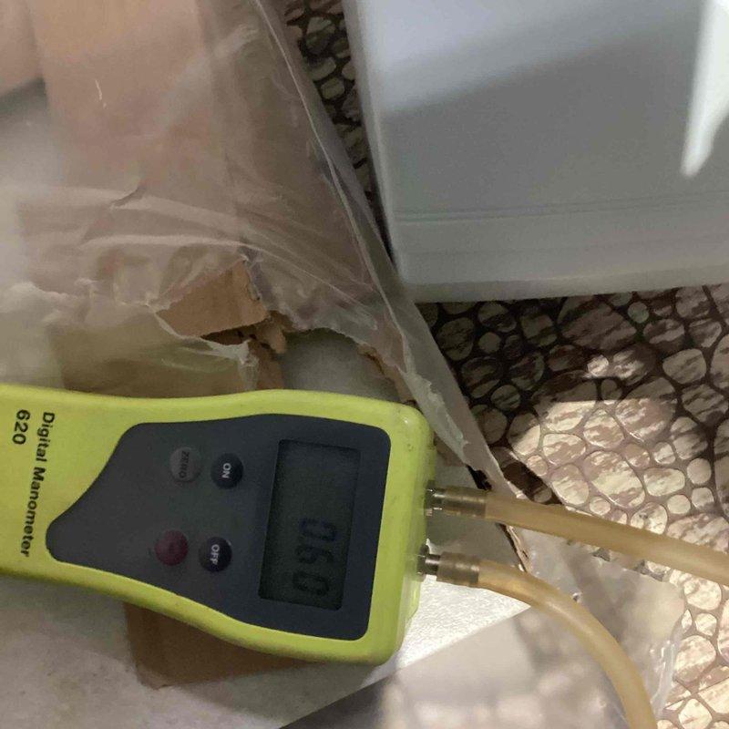 Performed a tune-up on a Carrier gas furnace, including inspection of the unit, vent piping, and condensate drain components. Used a digital manometer to check pressure readings during operation. Noted a displaced condensate pump/drain pan assembly near the unit and documented its condition for follow-up.