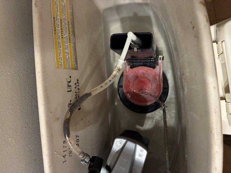 Diagnosed a reported hose bib leak and inspected the associated plumbing fixtures. The toilet tank assembly was also examined, revealing a worn, discolored rubber flapper, a corroded flush chain and lever arm, and mineral buildup on the fill valve and refill tube. Findings were documented with photos for further repair recommendations.
