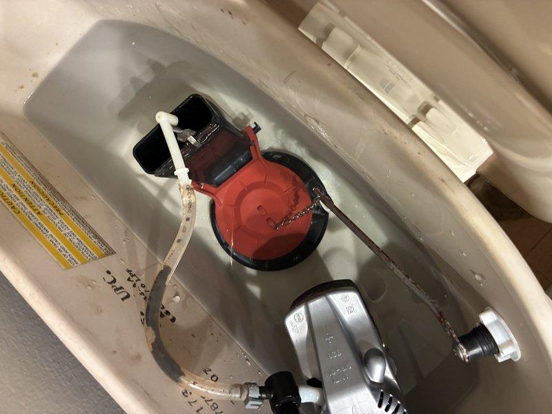 Diagnosed a reported hose bib leak and inspected the associated plumbing fixtures. The toilet tank assembly was also examined, revealing a worn, discolored rubber flapper, a corroded flush chain and lever arm, and mineral buildup on the fill valve and refill tube. Findings were documented with photos for further repair recommendations.