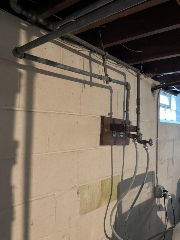 Performed a whole-home plumbing inspection, including the basement laundry area, water heater, utility sink, and visible drain, vent, and supply piping. Observed aged galvanized supply piping with surface corrosion and mineral buildup, washing machine supply valves and hoses, and staining on the foundation wall, with no active leaks or significant damage noted. Documented system conditions with photos and recommended monitoring the aging galvanized lines and supply hoses for future replacement.