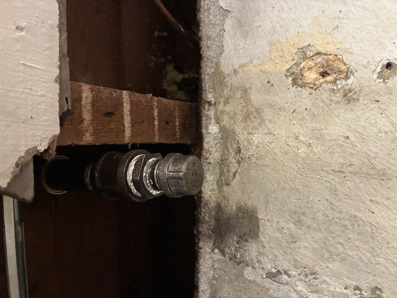 Assessed the site for a new gas line to the kitchen range and inspected the existing black iron piping, finding a capped threaded termination within the wall cavity adjacent to the concrete wall. Documented the cap, fittings, and joint condition (including mineral residue at the threads) and marked the pipe routing for the proposed extension, pending verification of capacity and code-compliant installation.