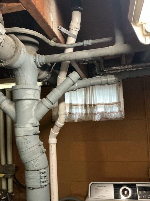 Repiped the laundry drain by replacing the existing section with new white PVC drain piping, connecting it to the main cast iron stack with no-hub couplings and banded clamps. Secured the new line with pipe hangers, verified the cleanout fitting remained accessible, and tested the washer discharge and utility sink drain to confirm proper flow with no leaks.