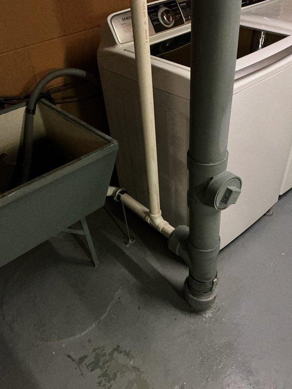 Repiped the laundry drain by replacing the existing section with new white PVC drain piping, connecting it to the main cast iron stack with no-hub couplings and banded clamps. Secured the new line with pipe hangers, verified the cleanout fitting remained accessible, and tested the washer discharge and utility sink drain to confirm proper flow with no leaks.