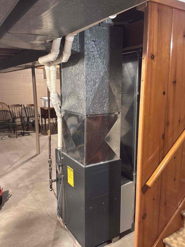 Performed an indoor air quality (IAQ) estimate, inspecting the Daikin gas furnace, galvanized supply plenum and ductwork, PVC venting, and the atmospherically vented water heater in the basement mechanical area. Equipment and ductwork appeared clean and in good condition with no visible rust, frost, or damage, and an existing cabinet-style device (air cleaner/humidifier) was noted on the supply duct. Documented the system with photos to evaluate IAQ improvement options.
