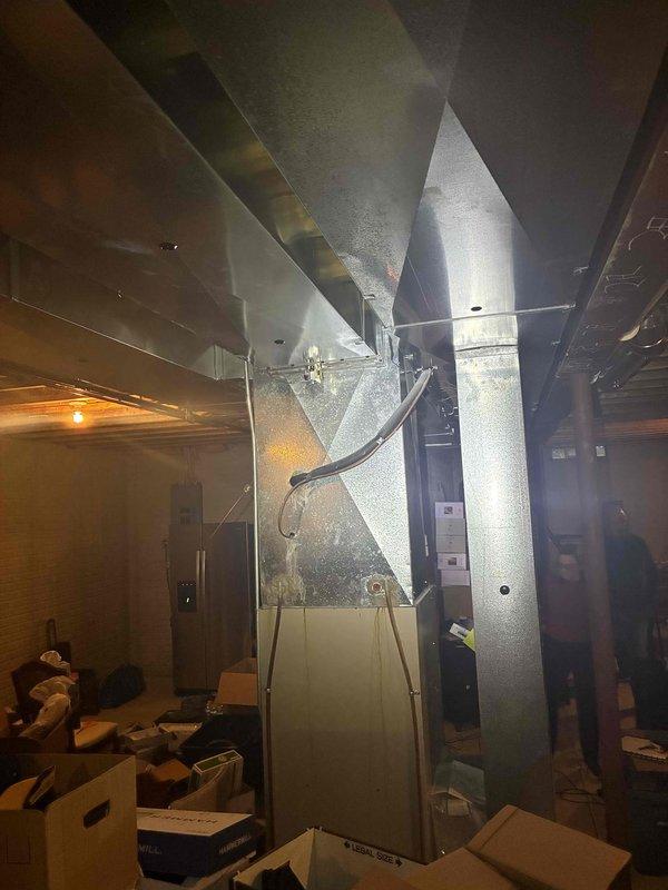 Performed an on-site evaluation for replacement of a 20+ year old natural gas furnace and matching air conditioning system, with the furnace located in the basement and previously shut down due to a failed heat exchanger. Inspected the furnace cabinet, burner and inducer assembly, control components, PVC venting, and existing ductwork transitions, noting corrosion near the inducer motor, and documented conditions with photos to prepare a same-day replacement estimate.