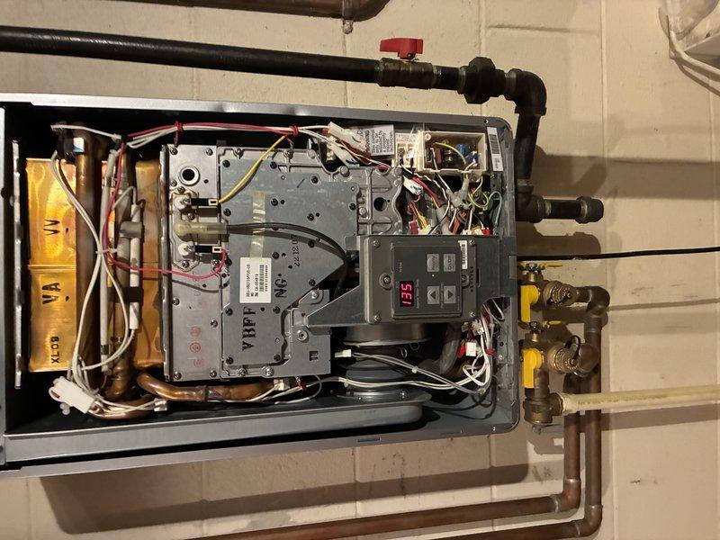 Diagnosed a gas-fired tankless water heater displaying error code 11 (ignition failure). Inspection of the burner compartment revealed heavy corrosion and rust debris on the burner assembly, flaking coating on the igniter/sensor bracket, and discoloration on the heat exchanger surfaces, indicating combustion and ignition reliability issues. Verified gas valve, blower, and wiring connections and documented findings with photos for repair recommendations.