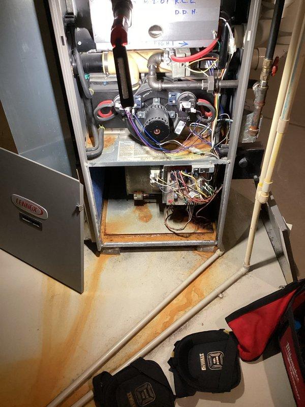 Responded to a no-heat call on a 10+ year old Lennox gas furnace with red and green diagnostic LEDs flashing. Inspection found the integrated furnace control board heavily scorched and burned around the relay and capacitor area, with dust and grime buildup throughout the control compartment. Significant corrosion was also present in the cabinet base pan, with rust staining running onto the floor, indicating prior moisture or condensate leakage; the board failure and corrosion were documented with photos for the customer's review and further recommendations.