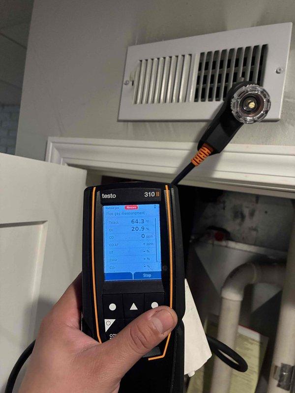 Responded to a reported gas leak at the furnace and performed a diagnostic evaluation with the gas supply shut off. Used a Testo 310 II flue gas analyzer to sample the surrounding area, recording CO levels of 7 ppm and 0 ppm with ambient O2 readings of 21.9% and 20.9%, indicating no hazardous combustion byproducts present. Noted soot-like discoloration on the closet interior, and the gas supply remains off pending further inspection and repair of the leak source.