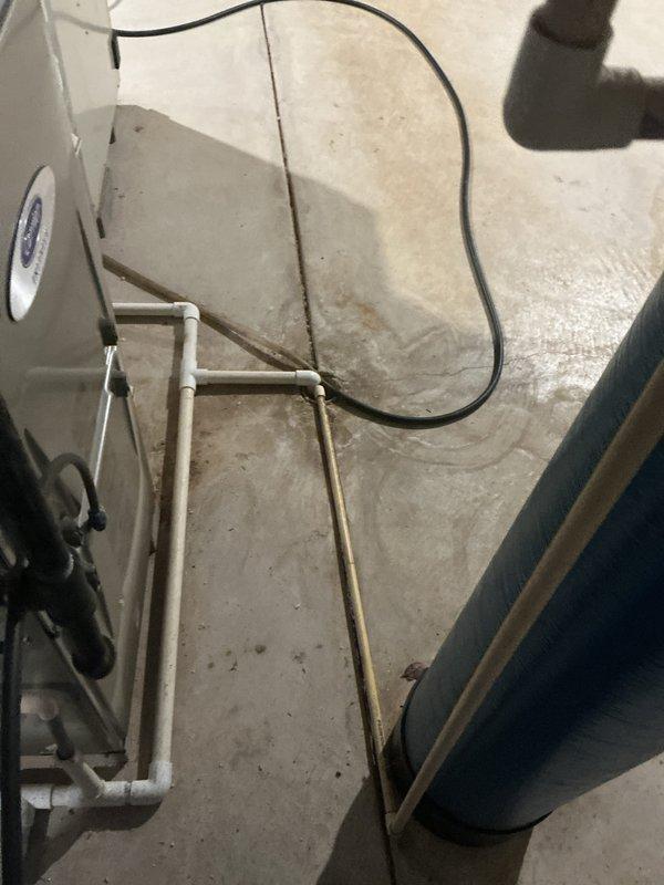 Conducted an on-site evaluation for replacement of an existing Carrier WeatherMaker Infinity high-efficiency natural gas furnace located in the basement mechanical area, with an associated Space-Gard air cleaner and galvanized supply trunk. Inspected the PVC vent and condensate piping, noting damp concrete flooring and staining near the condensate drain run and adjacent water treatment tank, and documented existing equipment condition with photos to support the replacement proposal.
