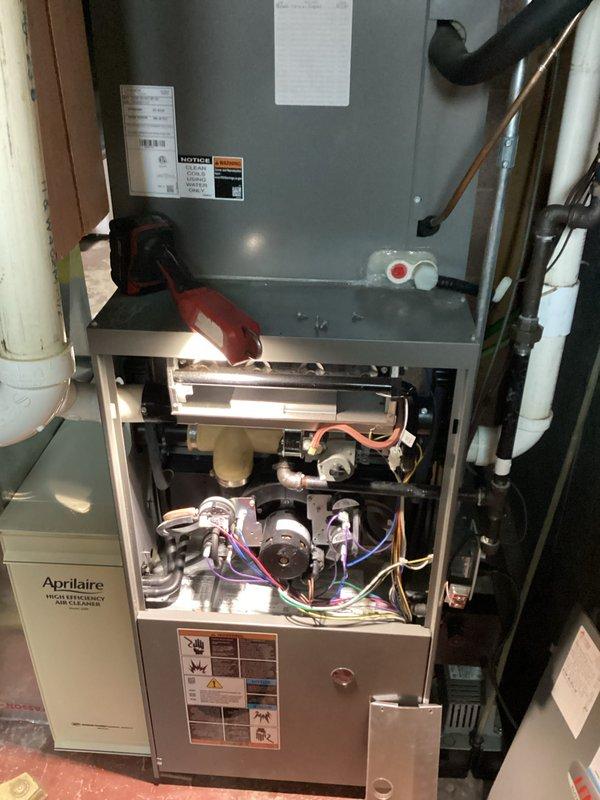 Performed a seasonal tune-up on a vertical gas furnace with an attached evaporator coil cabinet, inspecting the heat exchanger, draft inducer, pressure switch, blower motor, gas valve, and control wiring with the front panel removed. Verified condensate drain and PVC venting connections, checked the evaporator coil cabinet and associated components, and confirmed the Aprilaire air cleaner was in place. No frost, rust, or major damage observed, and the system was left in proper working order.