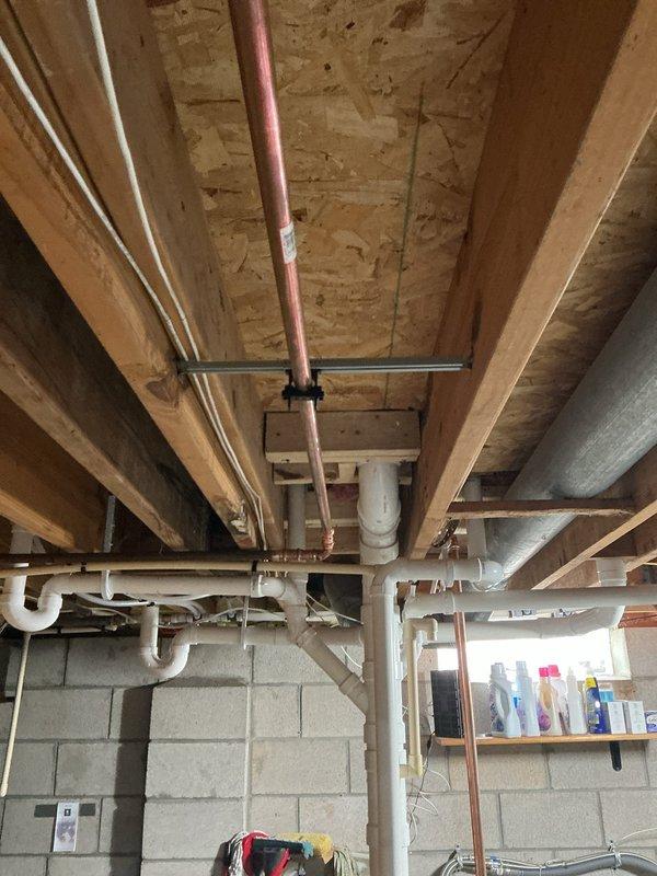 Repaired the water main by replacing approximately 20 feet of copper supply piping, with the water supply shut off for the duration of the work. The new copper run was secured to the floor joists with strut brackets and clamps, and the system was left properly supported and ready for service.