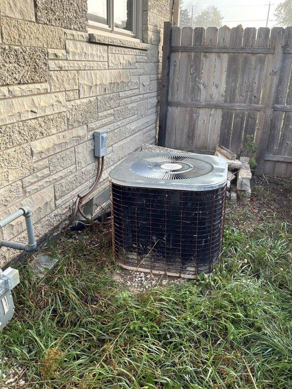 Performed a replacement estimate evaluation of the existing 36-year-old natural gas furnace located in the basement and the 19-year-old outdoor air conditioning condenser. The condenser exhibited heavily soiled, discolored coil surfaces with rust along the cabinet base and grate, and was surrounded by overgrown vegetation and debris restricting airflow. The condensate pump in the basement showed a corroded copper line at its inlet fitting, along with visible dust and debris buildup, and both systems were documented as candidates for replacement due to age and condition.