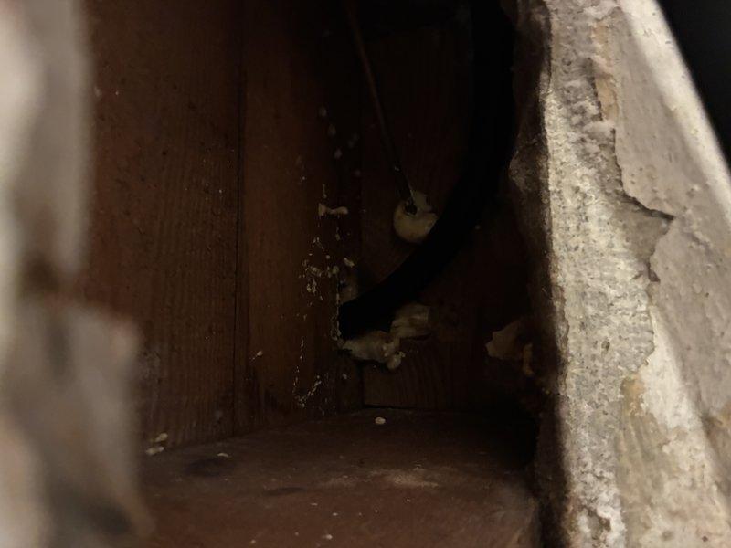 Installed a 3/4" black iron gas line to the stove location, routed through the wall cavity and terminated with a brass fitting and elbow connection to a flexible appliance connector. Sealed the pipe penetration through the framing with foam sealant to close the opening around the line.