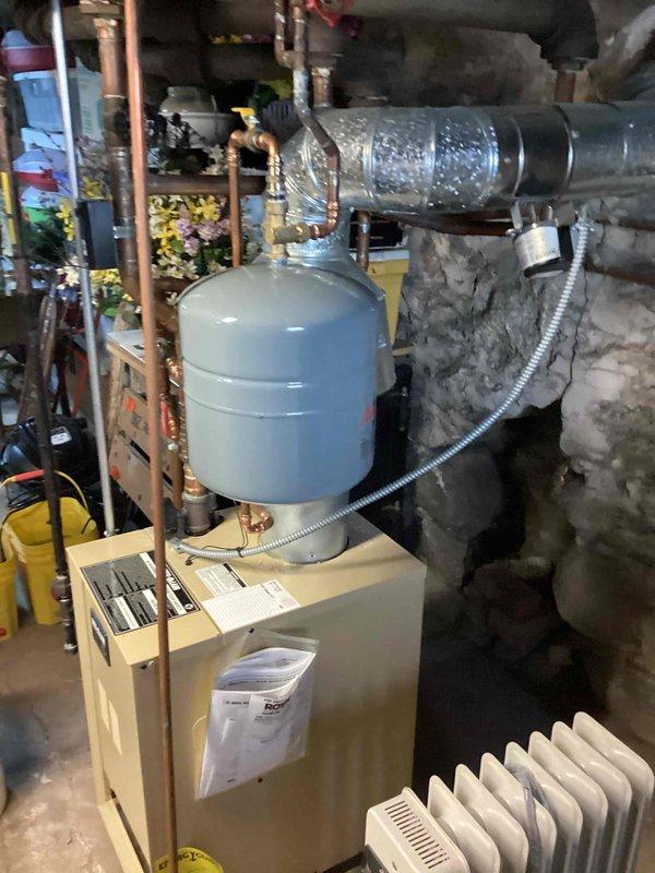 Performed annual tune-up on gas-fired boiler, inspecting the temperature/pressure gauge, expansion tank, and associated copper and brass piping and fittings, with no leaks, corrosion, or damage observed. Verified the flue venting to the chimney and flexible electrical conduit connections were secure and in good condition, and confirmed the unit was operating normally at completion.