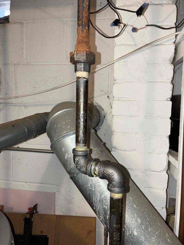 Responded to a hot water boiler heating complaint and inspected the basement-installed boiler system, including the zone valve and actuator wiring, supply piping, and gas piping. Observed heavy corrosion and mineral buildup on piping above the zone valve and rust on the gas line union fitting, both of which are noted as conditions requiring further evaluation. Documented system conditions with photos for the service record.