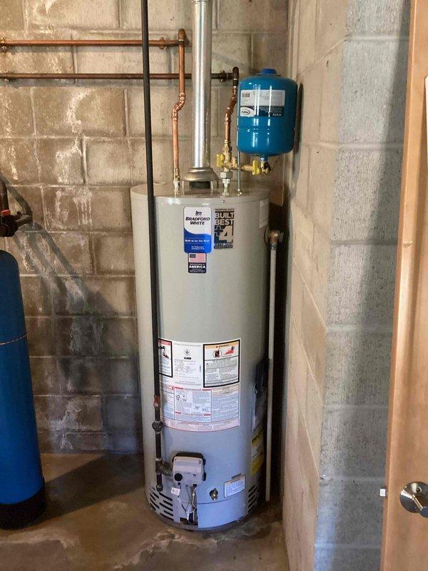 Installed a Bradford White gas-fired storage water heater with new copper supply piping, brass shutoff valves, and a thermal expansion tank, and connected the metal flue vent to the existing chimney path. Gas supply and burner assembly were connected and verified, with the unit operating normally and no leaks or visible damage observed.