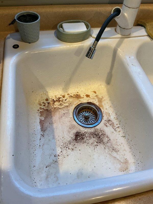 Diagnosed black particulate and rust-colored discoloration at the kitchen faucet cold supply, with photo documentation of heavy staining in the sink basin and inspection of the basement supply piping and shutoff valve. Evidence is consistent with corroded supply piping or deteriorating internal components releasing debris into the water line, and the exterior hose bib was also evaluated for the reported minor leak.