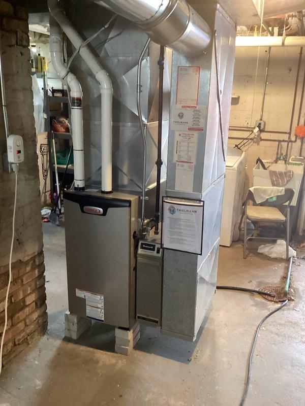 Installed a new upright gas furnace with a new thermostat, reusing the existing filter cabinet and adapting the new unit to the existing solid-core PVC venting. Reconnected the supply plenum and ductwork, set the furnace on elevated concrete blocks, and wired the control components, with permit obtained and electrical work completed. Unit is operating properly, with warning and rating labels, installation documentation, and the Honeywell control in place.