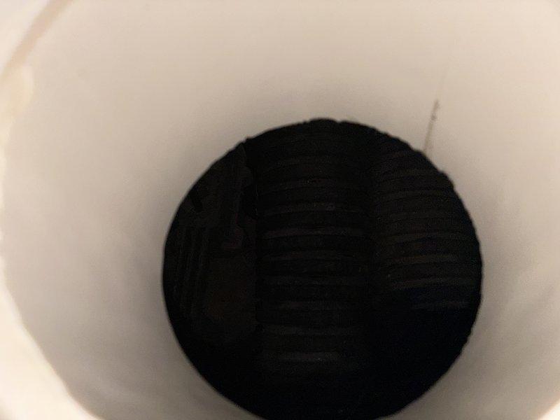 Performed a diagnostic inspection of the sump pump system, which had not been previously serviced, to verify operational condition. Inspected the discharge piping assembly, including the cleanout wye, PVC couplings, and the transition to the rusted pipe section at the sump basin cover, and observed the pit interior and flexible corrugated connection for obstruction or defects. Documented corrosion and buildup on the fittings and recommended further evaluation or maintenance as needed to ensure reliable operation.
