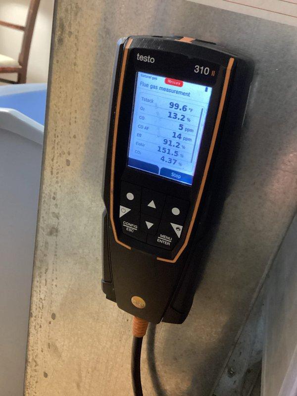 Performed a scheduled furnace tune-up as part of a recurring heating maintenance visit, including a combustion analysis with a Testo 310 II flue gas analyzer on natural gas. Readings were within normal range: 5 ppm CO (14 ppm air-free), 13.2% O₂, 4.37% CO₂, and 91.2% combustion efficiency. Also inspected the water inlet valve/pump assembly and hose connection, noting mineral deposits and signs of moisture on the surrounding floor.