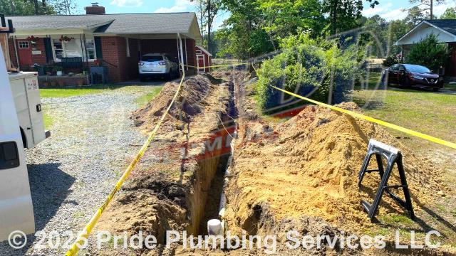 Pride Plumbing came out and 1) used an excavator to trench a ditch from the house to the town sewer tap to expose and remove the outside main sewer septic drain line; 2) installed a new 4-inch PVC sewer drain line (connecting it to the main drain line under the home) along with proper cleanouts and fittings per code; 3) installed tracer wire in the ditch along with the new sewer drain line; and 4) backfilled, tamped, and spread grass seed and straw after the work was inspected and approved by the county's Inspection Department.