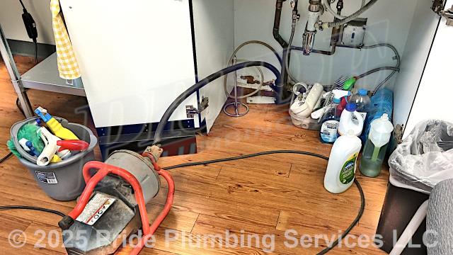 Pride Plumbing was called out for a water leak underneath a breakroom sink - the airgap was overflowing which indicated a blockage. We used a sewer machine down through the airgap drain and cleared the blockage. We tested for proper drainage with no further issues. We ran hot water down the sink for several minutes and it drained properly. We also provided a cost estimate to replace the kitchen sink's under-sink drain, airgap drain, P-trap, and drain line through the floor to under the building in the crawlspace, and to where it ties into the main sewer drain stack, with new PVC piping and fittings.
