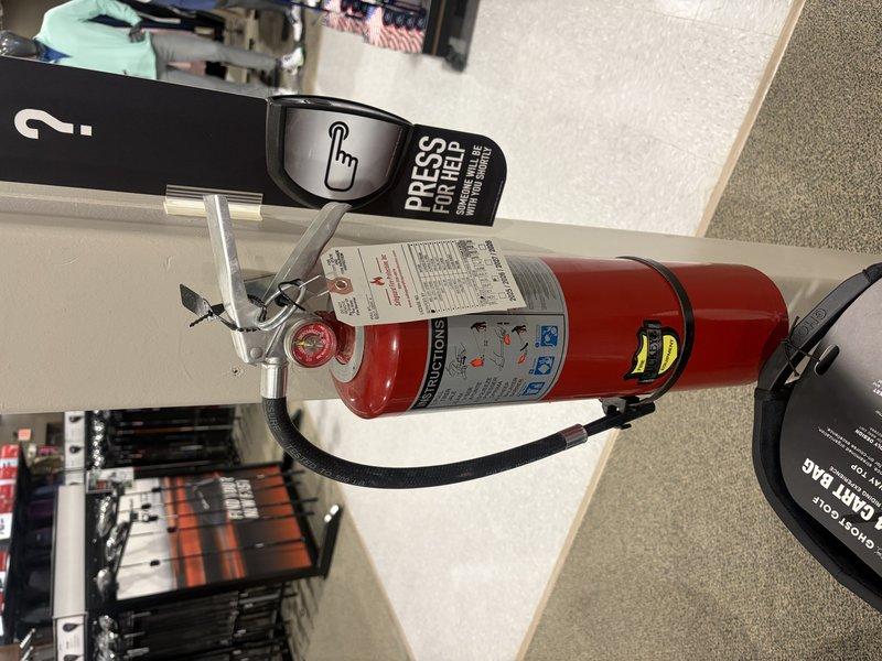 Completed annual fire extinguisher inspection at commercial facility. Inspected two fire extinguishers for compliance with NFPA standards, verifying proper pressure levels, pin and tamper seal integrity, hose condition, and label legibility. Confirmed both units were properly mounted with appropriate signage and accessibility. One ABC-type extinguisher located in retail area on floor level and one wall-mounted unit near exit with accompanying fire signage. All extinguishers passed visual inspection with no deficiencies noted. Updated inspection tags to reflect current service date.