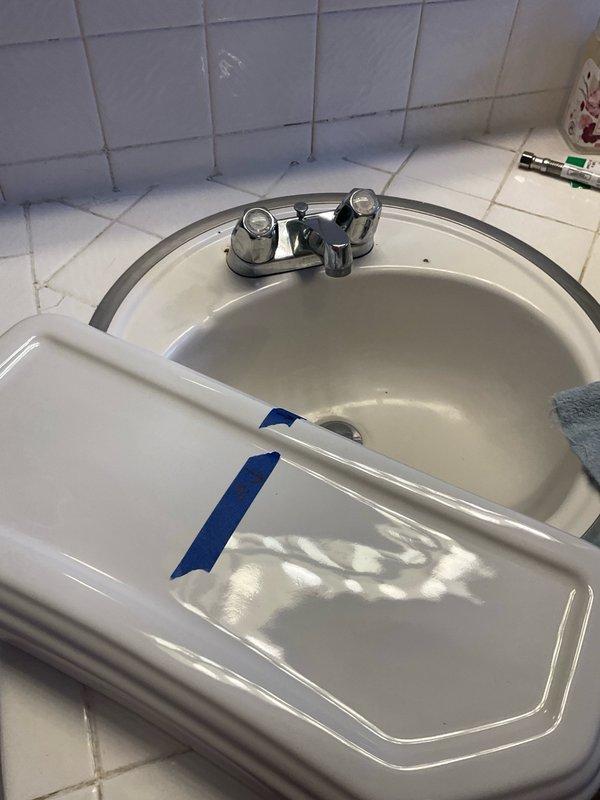 Conducted on-site assessment of bathroom fixtures requiring replacement. Evaluated existing two-handle faucet installation on oval porcelain sink basin with visible wear and staining. Inspected mounting configuration and existing supply line connections beneath vanity. Documented current fixture conditions including faucet hardware, shutoff valve accessibility, and drain assembly. Assessed second faucet location and toilet installation requirements. Photographed all fixtures and surrounding areas to prepare accurate material installation estimate for customer-supplied replacement components including two faucets, shutoff valves, and toilet assembly.