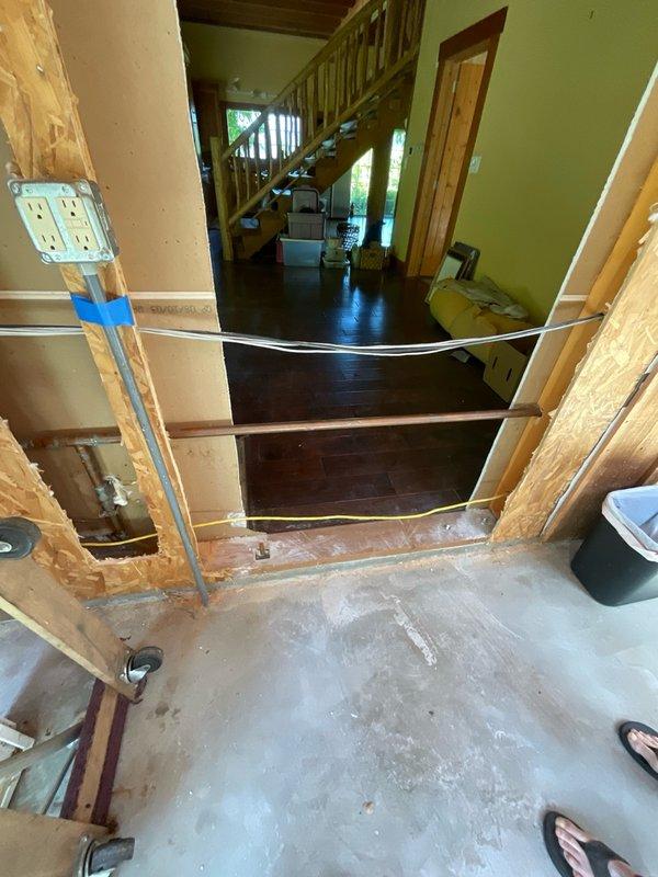 Responded to referral request to assess water pipe relocation required for new door installation in preparation for home sale. Conducted on-site diagnostic evaluation of existing plumbing configuration in unfinished basement area where copper water line conflicts with planned door framing. Documented current pipe routing through photo documentation showing transition between finished living space and construction zone. Identified supply line requiring rerouting to accommodate new door installation without compromising water distribution system integrity.