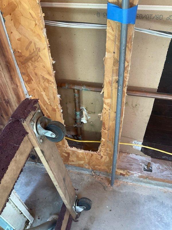 Completed diagnostic evaluation of plumbing infrastructure in residential renovation area. Documented existing conditions including exposed copper supply lines showing corrosion, shutoff valve assembly, flexible gas line routing, and vertical drainage piping. Photographed current state of rough plumbing installation and framing work for reference per scope outlined in estimate.