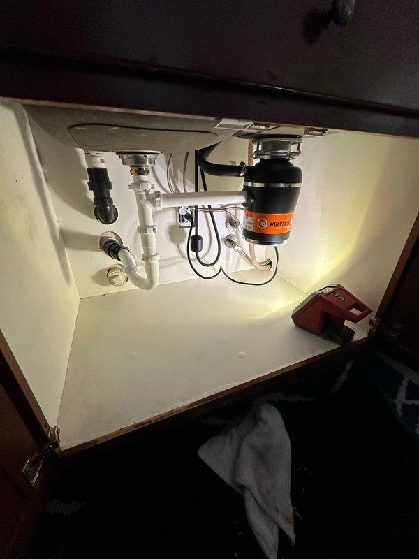 Responded to complaint of garbage disposal backing up and draining slowly. Upon arrival, accessed property using provided gate code and inspected kitchen sink area. Homeowner had already attempted basic troubleshooting including restarting unit, unplugging, and cleaning accessible portions of disposal.

Opened cabinet doors beneath double-basin stainless steel sink to examine Wolverine brand garbage disposal unit and associated plumbing. Conducted thorough inspection of disposal unit, drain connections, and P-trap configuration. Evaluated PVC drainage system for potential blockages, improper venting, or compromised pipe integrity that could cause slow drainage issues.

Tested disposal operation and observed drainage performance. Checked electrical connections to ensure proper power supply to unit. Examined mounting assembly and discharge elbow connection to drainage system. Assessed P-trap and downstream piping for debris accumulation or partial obstruction. Documented existing install