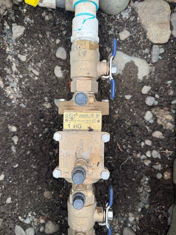 Responded to service call for irrigation valve system evaluation in garage area. Performed comprehensive diagnostic assessment of irrigation system components including pressure testing at outdoor spigot and inspection of pressure reducing valve assembly. Testing revealed zero PSI reading at hose bib connection point, indicating potential system pressurization issue or valve malfunction. Documented condition of brass pressure reducing valve (model 850) installed on PVC piping with visible weathering and outdoor exposure. Noted grounding wires properly attached to valve assembly. Captured photographic documentation of all system components for reference. Provided complimentary estimate and presented multiple repair options to address identified pressure regulation concerns and restore proper irrigation system functionality.