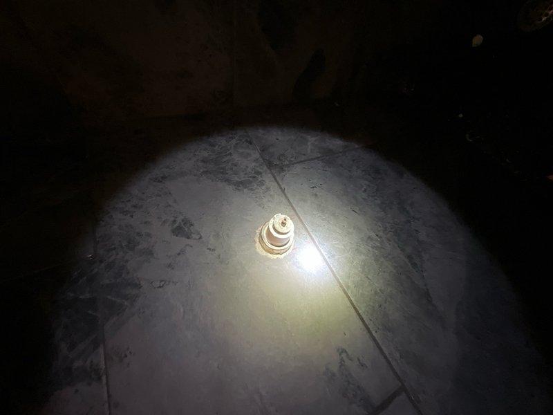 Responded to service call to inspect shower handle. Upon arrival, accessed crawl space beneath bathroom to examine plumbing connections and mounting hardware from below. Documented existing conditions with photos showing concrete floor surface and underside access point where shower valve assembly is located. No immediate repairs performed during this diagnostic visit.