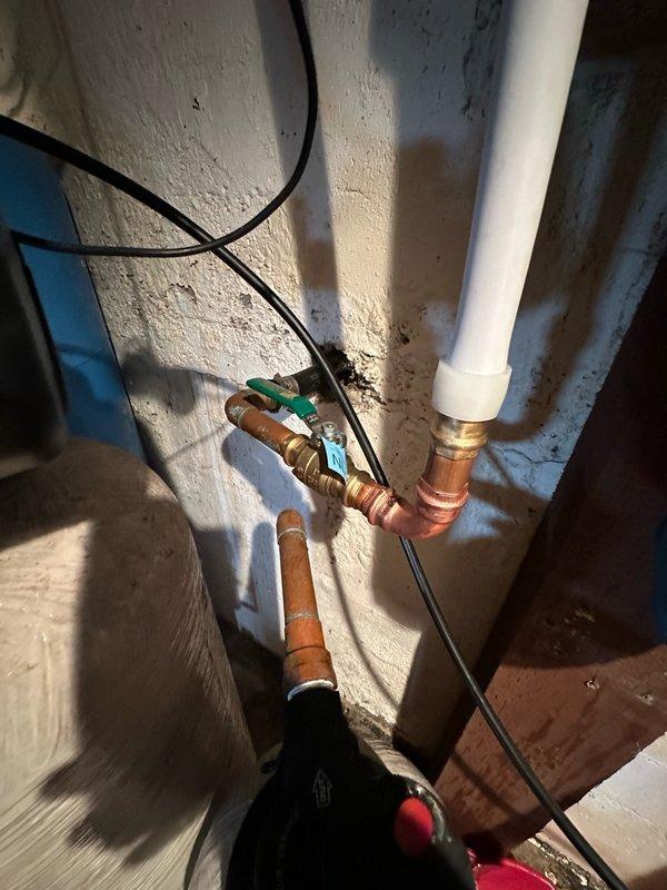 Completed diagnostic assessment of residential water filtration system. Inspected blue cylindrical water filter housing mounted to structural support, evaluated condition of copper and PVC plumbing connections, brass fittings, and associated pressure tank. Documented existing equipment configuration including water treatment control unit, valve assemblies, and piping layout for filter replacement planning.