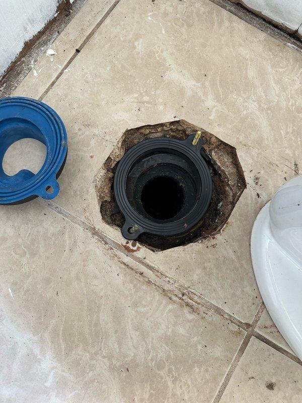 Responded to diagnostic service call for plumbing assessment. Upon arrival, inspected floor drain system showing significant water staining and discoloration on surrounding tile work, indicating potential drainage issues or past water intrusion. Drain assembly featured black rubber flange with concentric ridges set within octagonal tile opening. Documented condition with photographs for reference and further evaluation.

Assessed removed plumbing fixtures including two white porcelain sinks exhibiting heavy staining, mineral deposits, and deterioration around drain areas. Inspected collection of salvaged plumbing components including various pipe fittings, valve assemblies, and green ductwork sections stored in cardboard container. All fixtures and hardware appeared to be part of renovation or replacement project in progress. Provided diagnostic findings and recommendations for proper drainage system maintenance and fixture replacement considerations.