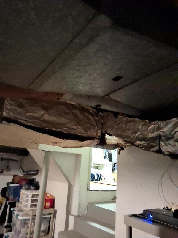 Conducted site assessment for ductwork estimate revision following structural modifications made by customer to basement wall area. Documented exposed ceiling infrastructure, displaced insulation, and damaged attic framing where wooden beams have collapsed, creating unsafe conditions with debris and compromised ductwork routing that will require new estimate calculations for proper HVAC system installation.