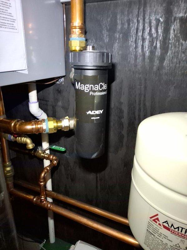 Responded to water leak complaint on recently installed water heater. Upon inspection, discovered minor leak originating from plumbing connections near the MagnaClean Professional magnetic filter system. Identified loose compression fitting on copper supply line entering the filtration unit. Tightened brass compression fittings, verified all connections on associated copper piping, and confirmed proper seal at water heater inlet. Inspected pressure relief valve, expansion tank, and all visible joints for additional moisture. Cleaned up standing water, monitored system under pressure, and confirmed leak resolved with no further water accumulation detected.