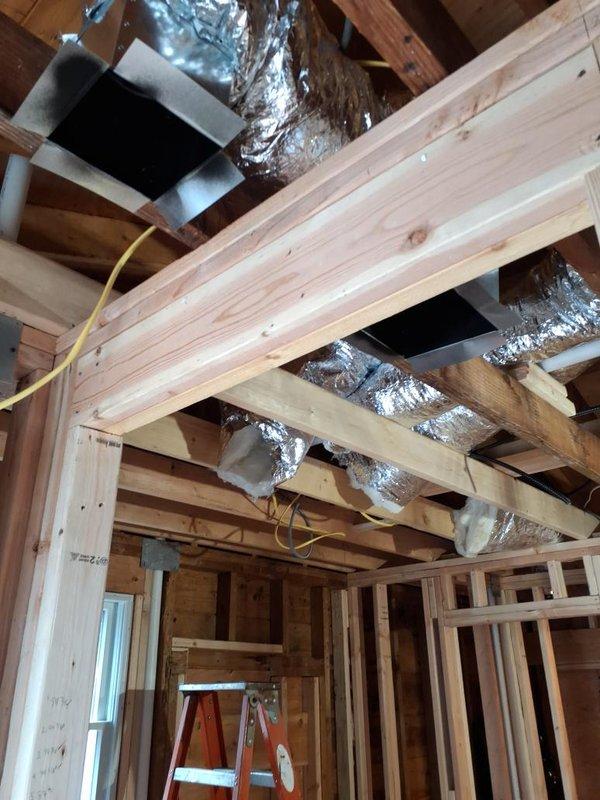 Completed HVAC system rough-in installation in residential construction space, including flexible ductwork runs between ceiling joists, electrical conduit installation for system power, and recessed lighting fixture integration. Installed duct transitions and register boots at designated locations, with all mechanical components properly secured to structural framing per building code requirements.