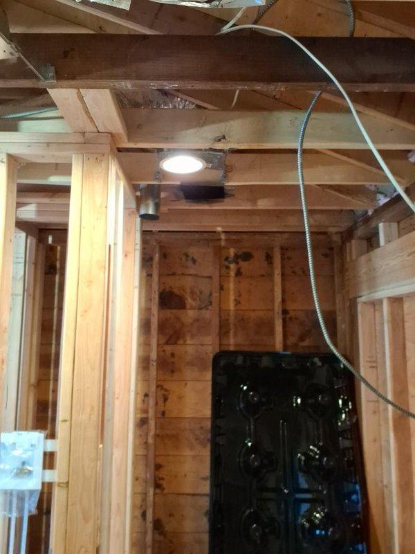 Completed HVAC system rough-in installation in residential construction space, including flexible ductwork runs between ceiling joists, electrical conduit installation for system power, and recessed lighting fixture integration. Installed duct transitions and register boots at designated locations, with all mechanical components properly secured to structural framing per building code requirements.