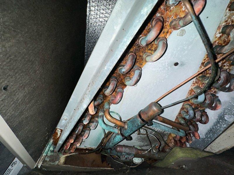 Completed seasonal maintenance on two air conditioning systems. First unit exhibited severe coil corrosion with extensive oxidation on copper tubing showing multiple colors of patina, indicating prolonged moisture exposure and chemical degradation. Second unit contained substantial accumulation of organic debris including grass, leaves, and nesting material that was removed from the interior housing. Both systems were inspected, cleaned, and serviced per manufacturer specifications to restore proper operation.