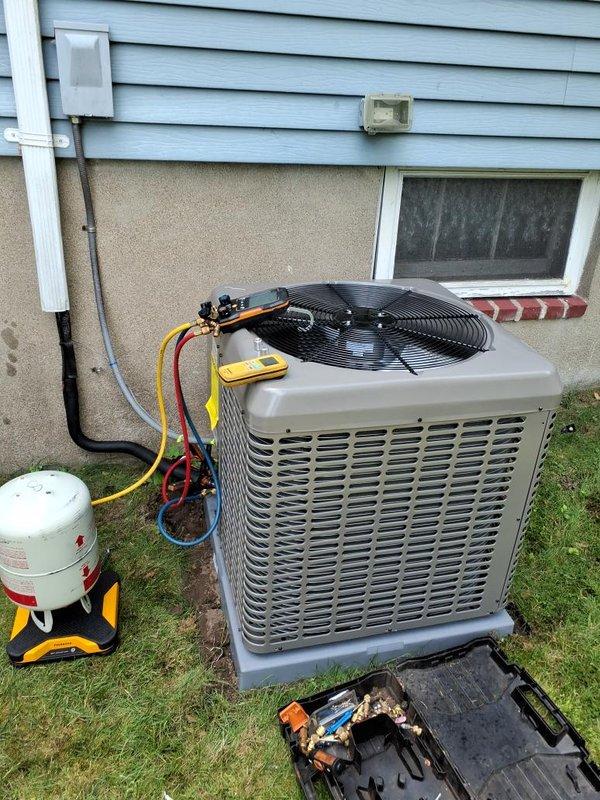 Completed installation of new residential air conditioning condenser unit on exterior concrete pad. Installed refrigerant lines with proper insulation and secured line set to building exterior using appropriate mounting hardware and protective conduit. Performed system evacuation using vacuum pump to remove moisture and contaminants from refrigerant lines. Charged system with refrigerant to manufacturer specifications using manifold gauge set and recovery equipment. Verified electrical connections at disconnect box and tested unit operation. Confirmed proper airflow through condenser fan and checked all service valves for secure connections and proper sealing.