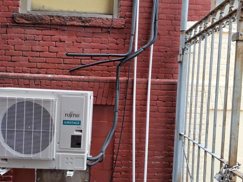 Installed Fujitsu Airstage outdoor condenser units on exterior brick wall for classroom HVAC system. Mounted units with proper brackets, ran refrigerant line sets with foam insulation vertically along wall, and installed electrical conduit with appropriate routing to connect power and controls to the condensers.