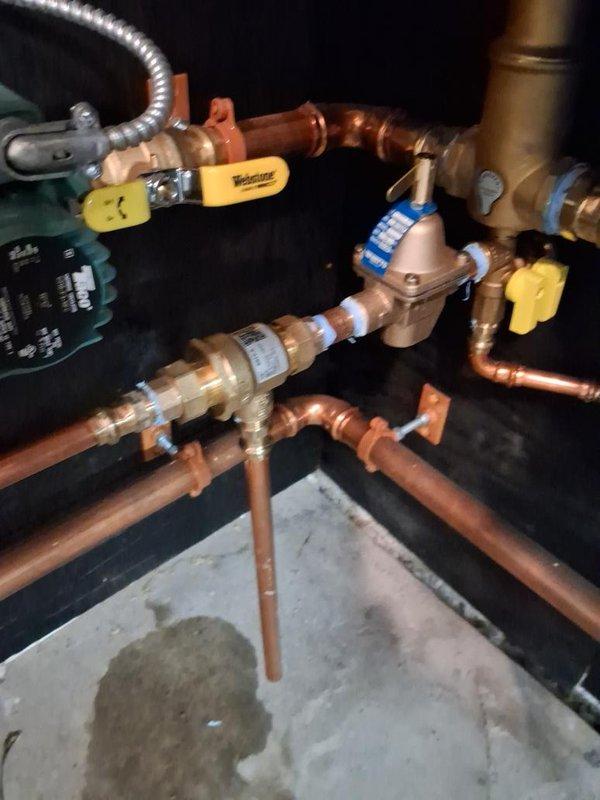 Responded to no hot water call during scheduled 8am-10am arrival window for boiler system evaluation. Upon inspection, diagnosed issues with the heating system's pressure regulation and circulation components. Examined the pressure and temperature gauge assembly, which monitors both PSI (0-80 range) and temperature (0-250°F range) to ensure proper system operation. 

Inspected the main valve manifold configuration consisting of multiple copper pipe connections with ball valves for system isolation and flow control. Evaluated the central pressure regulator component and associated brass fittings that control water pressure throughout the heating distribution system. Checked all valve positions and verified proper operation of isolation valves equipped with yellow handles for maintenance access points.

Assessed the circulation pump and control unit for proper electrical operation and mechanical function. Examined flexible connector hoses and verified integrity of all copper pipe joints 