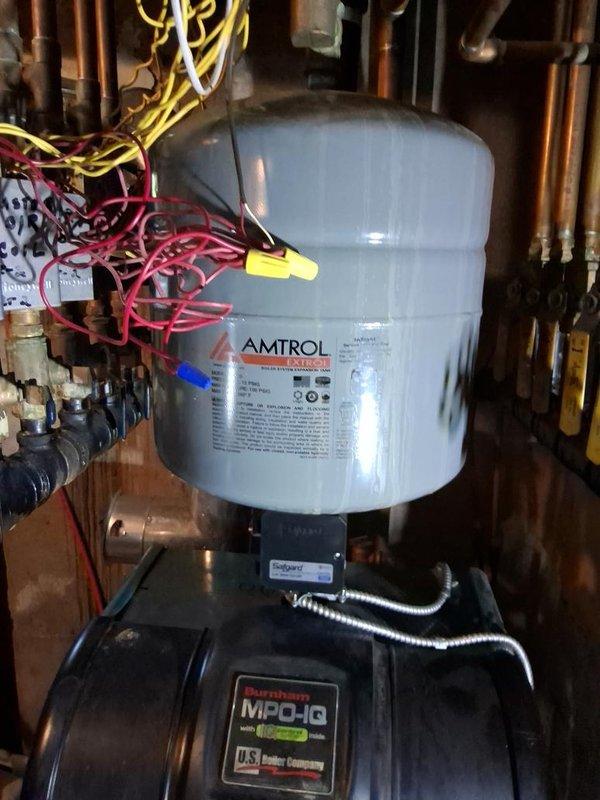 Responded to service call for water dripping from boiler and water smell associated with AC operation. Upon arrival, inspected hydronic heating system including AMTROL expansion tank, Burnham MPO-IQ circulating pump, and associated copper piping network. Examined AC unit components including compressor, refrigerant lines, and copper coil assembly for signs of condensate leakage or drainage issues. Verified AC units were operating and providing adequate cooling. Documented system conditions with photographs showing plumbing connections, pressure tank installation, and HVAC components. Customer reported water smell dissipated when AC units were turned off, suggesting potential condensate drain concern rather than boiler leak.