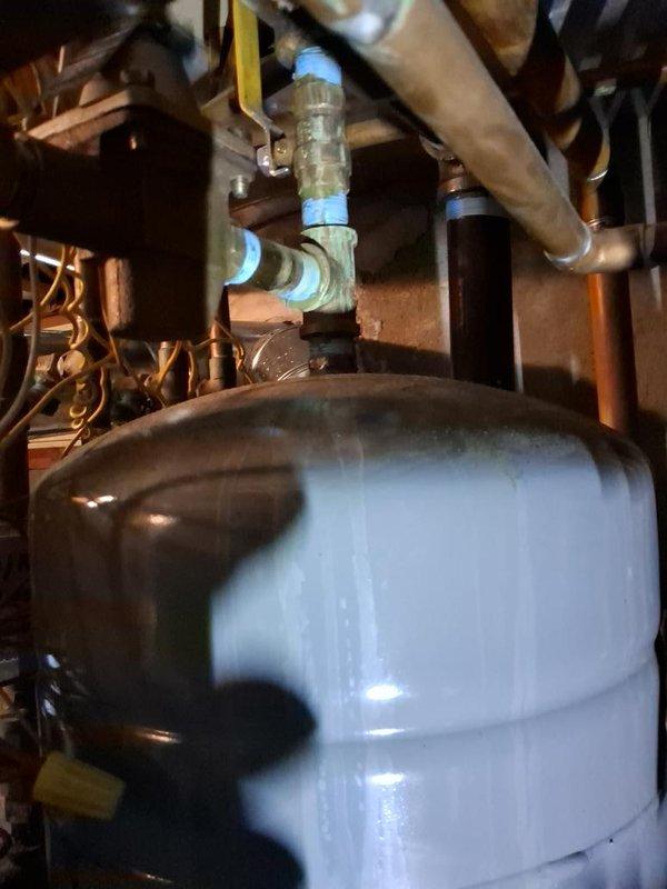 Responded to service call for water dripping from boiler and water smell associated with AC operation. Upon arrival, inspected hydronic heating system including AMTROL expansion tank, Burnham MPO-IQ circulating pump, and associated copper piping network. Examined AC unit components including compressor, refrigerant lines, and copper coil assembly for signs of condensate leakage or drainage issues. Verified AC units were operating and providing adequate cooling. Documented system conditions with photographs showing plumbing connections, pressure tank installation, and HVAC components. Customer reported water smell dissipated when AC units were turned off, suggesting potential condensate drain concern rather than boiler leak.