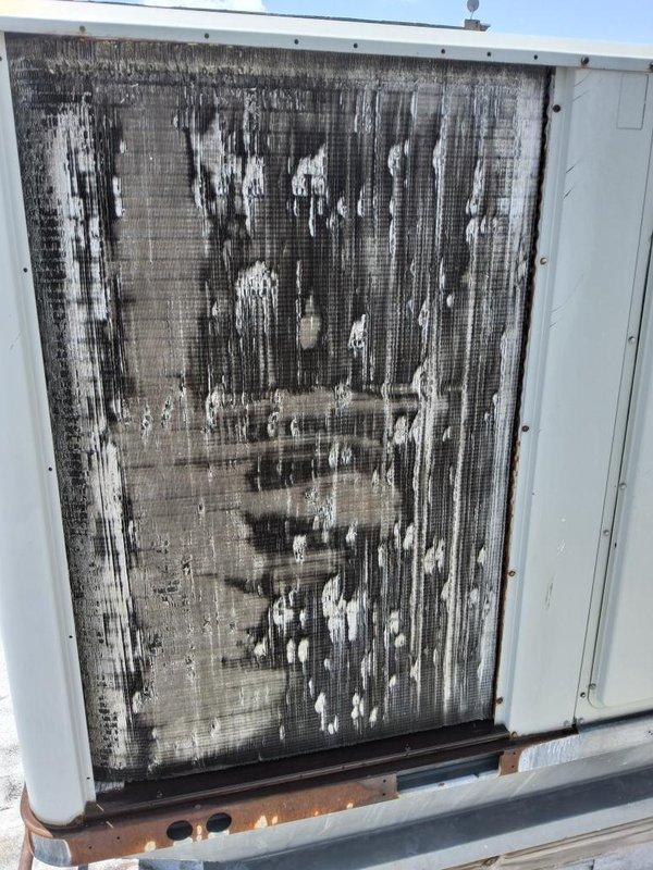 # No AC Service Completed

Responded to a commercial refrigeration complaint regarding insufficient cooling. Upon arrival, conducted a thorough inspection of the rooftop HVAC unit and discovered severely deteriorated condenser coil with extensive biological growth, dirt accumulation, and dark vertical streaking patterns covering the entire coil surface. The heavy contamination was significantly restricting airflow and reducing heat transfer efficiency, directly causing the inadequate cooling performance.

Performed complete condenser coil cleaning using professional-grade coil cleaner and pressure washing equipment to remove years of accumulated debris, algae, and environmental contaminants. Restored coil fins to proper condition and verified unrestricted airflow through the unit. Inspected drain pan and found rust-colored staining; cleared drain ports to ensure proper condensate drainage. Checked all electrical connections, refrigerant pressures, and system operation following cleanin
