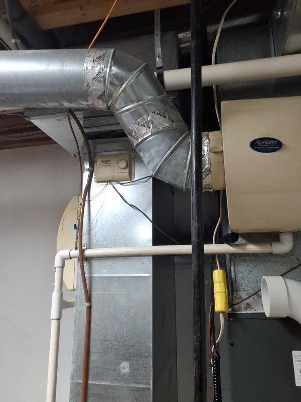 Responded to no heat call for Trane XR90 furnace serving main residence. Homeowner reported control board not illuminating despite verifying power supply, attempting reset, and replacing fuse. Upon inspection, confirmed Emerson control board had no power indication or LED status lights. Outdoor condensing unit was operational, indicating issue isolated to indoor air handler. Documented existing installation including ductwork configuration, Aprilaire humidifier integration, and control board wiring connections. Photographed control board showing multiple wire terminations, wire nuts, and component layout for diagnostic reference. Recommended control board replacement to restore heating operation.