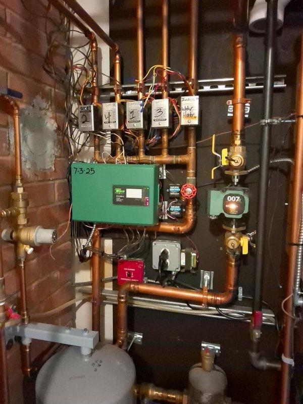 Responded to no hot water call for NTI TRX199C combi boiler that experienced repeated motherboard failures after recent replacement by another contractor. Upon inspection of the hydronic system, documented the existing installation including the combi boiler, expansion tanks, zone pumps, and associated copper piping with brass fittings. Assessed the system for underlying electrical issues that may have caused the secondary motherboard failure. Photographed the complete mechanical room setup showing the water heater, green control boxes, circulation components, and piping configuration to support warranty claim documentation, as unit is covered under manufacturer warranty.