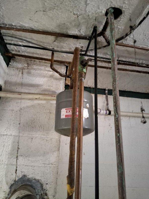 Conducted comprehensive site assessment for complete boiler replacement and fuel conversion from oil to natural gas. Evaluated existing heating system infrastructure, including aged copper piping with significant oxidation, expansion tank, and associated plumbing components mounted throughout the utility space. Documented current mechanical configuration, pipe routing, electrical connections, and structural mounting conditions. Photographed existing equipment and distribution systems to support conversion specifications. Prepared detailed estimate for removal of oil-fired boiler system and installation of new gas-fired unit, including necessary gas line installation, venting modifications, and integration with existing hydronic distribution network.