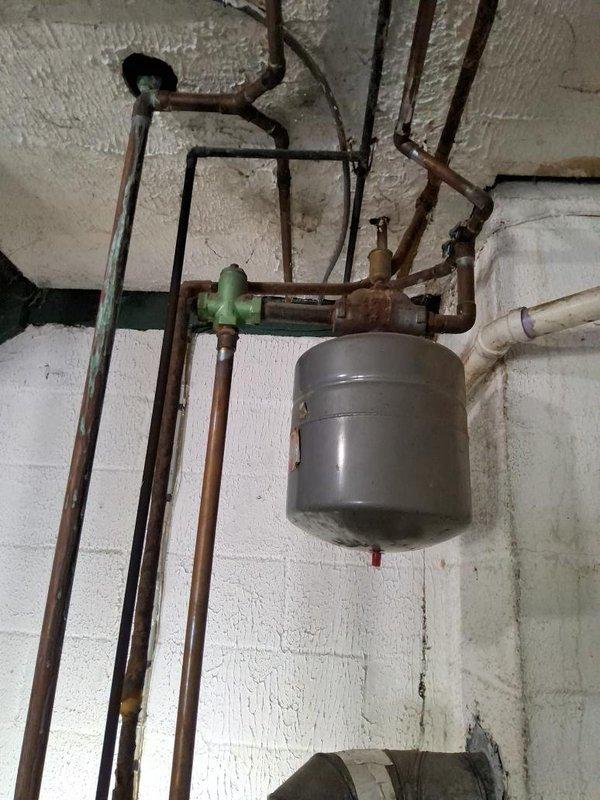 Conducted comprehensive site assessment for complete boiler replacement and fuel conversion from oil to natural gas. Evaluated existing heating system infrastructure, including aged copper piping with significant oxidation, expansion tank, and associated plumbing components mounted throughout the utility space. Documented current mechanical configuration, pipe routing, electrical connections, and structural mounting conditions. Photographed existing equipment and distribution systems to support conversion specifications. Prepared detailed estimate for removal of oil-fired boiler system and installation of new gas-fired unit, including necessary gas line installation, venting modifications, and integration with existing hydronic distribution network.